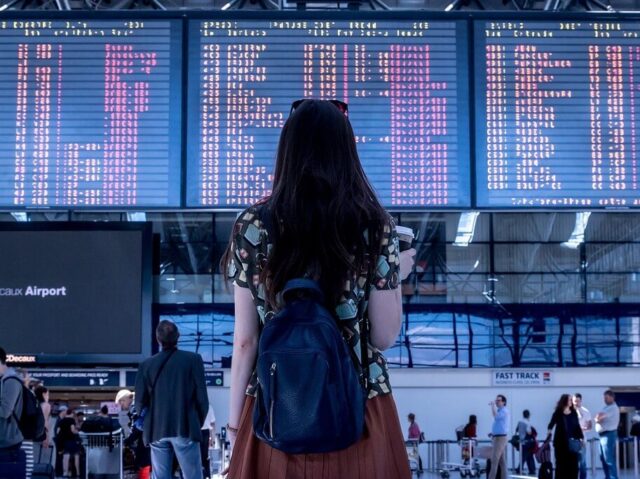 空港で電子掲示板を見る女性