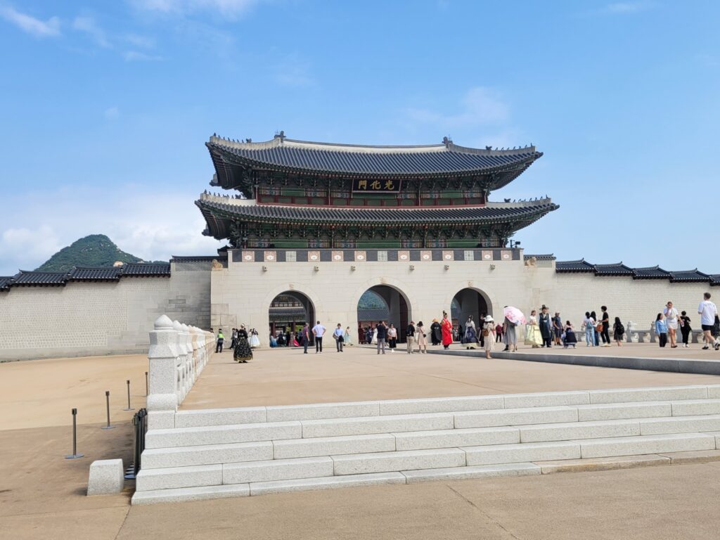 青空の下に建つソウル景福宮の正門・光化門と観光客